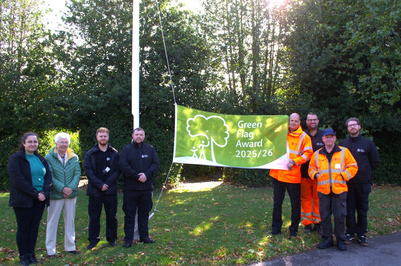People standing around the Elmfield Park green flag. 